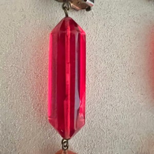 May include: A pair of vintage earrings with a red faceted glass teardrop pendant and a clear faceted glass teardrop pendant. The earrings are attached to a silver clip-on earring.