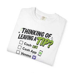Könnte beinhalten: Ein weißes T-Shirt mit dem schwarzen und grünen Text "THINKING OF LEAVING A TIP?" über einer Checkliste mit drei Optionen: "Cash" mit einem Geldschein-Symbol, "Cash App" mit einem Smartphone-Symbol und "Venmo" mit einem violetten Logo-Symbol.