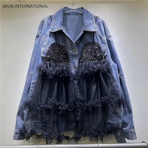 May include: A blue denim jacket featuring a black sequined bodice overlay with tiered black tulle ruffles. The jacket has a classic collar, long sleeves, and a button-front closure. The text SBUN INTERNATIONAL is printed in the top left corner.