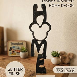 May include: A black vertical sign spelling the word HOME with a Mickey Mouse silhouette replacing the letter O. The sign features a glitter finish and includes the text HAND-CRAFTED DISNEY-INSPIRED HOME DECOR, GLITTER FINISH!, PERFECT GIFT FOR DISNEY LOVERS, and MADE WITH LOVE.
