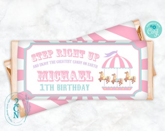 Könnte beinhalten: Rosa und blauer Schokoladenriegel-Wrapper mit Zirkus-Thema. Es steht "Step Right Up and Enjoy the Greatest Candy on Earth" mit dem Namen "Michael" und "1st Birthday" darunter. Es gibt ein rosafarbenes und weißes Karussell mit Pferden darauf.