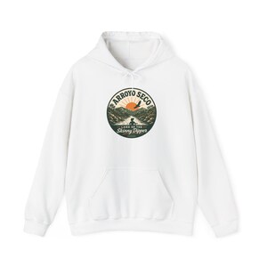 May include: A white hooded sweatshirt featuring a circular graphic on the chest. The design depicts a landscape with mountains, a river, a rising sun, and a bird in flight. The text reads Arroyo Seco and Land of the Skinny Dipper.