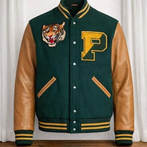 Puede incluir: Una chaqueta universitaria de color verde oscuro con mangas de cuero color canela, con un parche de cabeza de tigre en el pecho derecho y una letra P amarilla grande en el pecho izquierdo. La chaqueta tiene cuello, puños y dobladillo acanalados con rayas.