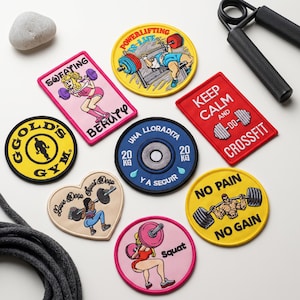 May include: A collection of embroidered patches featuring fitness themes, including a Gold's Gym logo, a blue 20 kg weight plate, and various illustrations of people lifting weights with text like Powerlifting Is Life, Keep Calm and Do CrossFit.