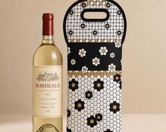 Puede incluir: Una botella de vino de cristal transparente con etiqueta de Bordeaux Sauvignon Blanc junto a un portabotellas de neopreno rectangular. El portabotellas presenta un patrón geométrico de panal en negro, blanco y oro con motivos florales.