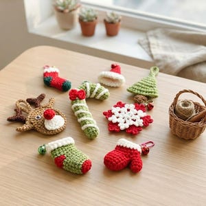 May include: A collection of crocheted Christmas ornaments including a reindeer, a candy cane, a snowflake, a green tree, a red mitten, and two stockings, arranged alongside a small woven basket containing a ball of yarn and a cinnamon stick.