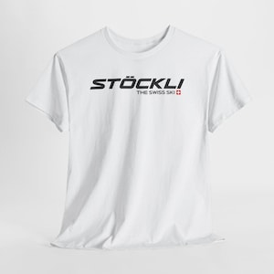 Op de afbeelding: Een wit T-shirt met korte mouwen voorzien van de zwarte tekst STÖCKLI en de woorden THE SWISS SKI gevolgd door een klein rood vierkant met een wit kruis, gecentreerd op de borst van het kledingstuk.