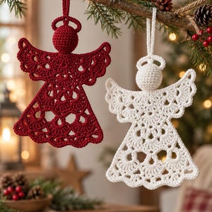 May include: Two crocheted angel ornaments hanging from a branch. One angel is deep red and the other is off-white. Each features a circular head with a halo, outstretched wings, and a flared skirt, all crafted with a detailed, openwork lace pattern.