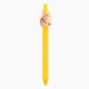 Peut inclure: Un stylo à bille rétractable jaune vif doté d'une petite breloque plate en acrylique translucide fixée près du sommet. La breloque présente une illustration détaillée et réaliste d'un chat brun clair assis dans une position calme et droite.