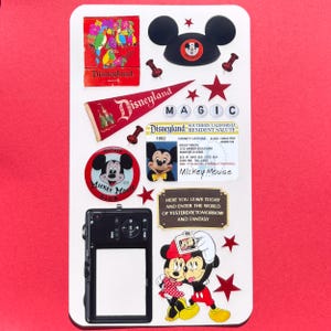 May include: A white rectangular board decorated with Disneyland memorabilia including a red pennant, a 1992 resident license, a Mickey Mouse Club pin, a black camera frame, and a graphic of Mickey and Minnie Mouse with the text Magic and Here You Leave Today.