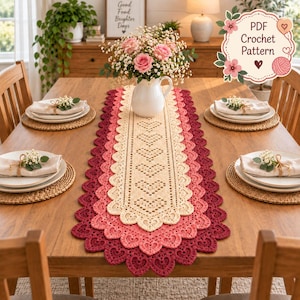 May include: A rectangular crochet table runner featuring a repeating heart pattern in cream, light pink, and dark pink. The runner has a scalloped edge with heart-shaped motifs. A white vase with pink roses sits on the runner. Text reads PDF Crochet Pattern.