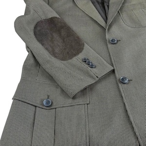 May include: A grey and black houndstooth blazer featuring dark brown suede elbow patches, a notched lapel, three buttons on the sleeve cuffs, and two front flap pockets with button closures. The garment is constructed with a structured collar.