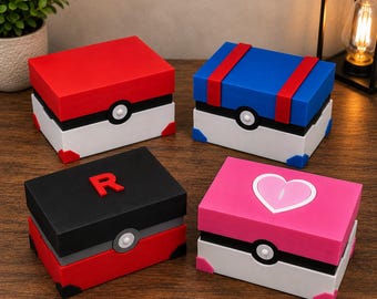 May include: Four rectangular storage boxes designed like game-inspired spheres. One is red and white, one is blue and white with red stripes, one is black and red with a letter R, and one is pink and white with a heart icon. Each features a central button.