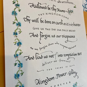 Puede incluir: Una versión manuscrita del Padre Nuestro en tinta negra sobre fondo blanco. El texto está enmarcado por un borde decorativo de flores azules y verdes. El texto dice: "Padre nuestro que estás en los cielos, santificado sea tu nombre, venga tu reino, hágase tu voluntad en la tierra como en el cielo. Danos hoy nuestro pan de cada día, y perdónanos nuestras deudas, como también nosotros perdonamos a nuestros deudores. Y no nos dejes caer en la tentación, mas líbranos del mal. Porque tuyo es el reino, y el poder, y la gloria, por siempre jamás. Amén."