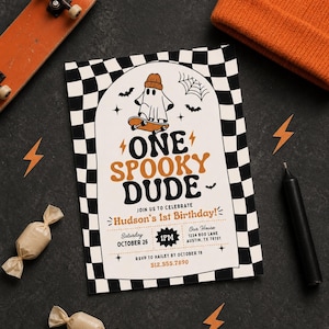 May include: A rectangular birthday invitation card with a black and white checkered border. The center features a ghost wearing an orange beanie on a skateboard, with the text ONE SPOOKY DUDE, Hudson's 1st Birthday, October 26, 1PM, and contact details.
