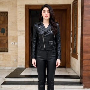 May include: A black leather motorcycle jacket with a silver asymmetrical zipper, notched lapels, and zippered pockets, paired with matching black leather trousers and black lace-up ankle boots. The outfit features a consistent dark aesthetic.