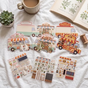 May include: A collection of die-cut stickers and sticker sheets featuring illustrated food trucks and shops, including an ice cream truck with polar bears, a flower shop, and a cheeseburger truck, alongside matching decorative sticker elements.