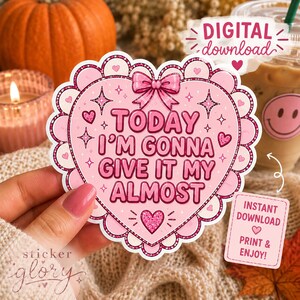 May include: A heart-shaped sticker with a scalloped border featuring a pink bow at the top and the text "TODAY I'M GONNA GIVE IT MY ALMOST" in dark pink letters. The design includes small glittery hearts and star accents on a light pink background.