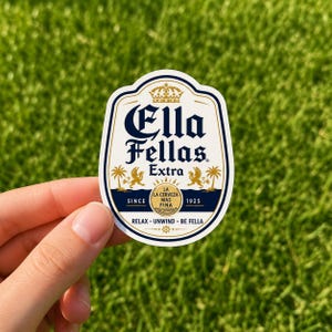 May include: A die-cut sticker featuring a white background with a dark blue and gold border. The text reads Ella Fellas Extra, with graphics of palm trees, lions, and a crown. Additional text includes Since 1925, La Cerveza Mas Fina, and Relax - Unwind - Be Fella.