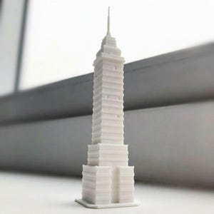 Può includere: Un modello in miniatura stampato in 3D di colore bianco che rappresenta il grattacielo Torre Latinoamericana. La struttura presenta un design rettangolare a gradoni con una guglia centrale sulla sommità, una finitura opaca e dettagli architettonici.