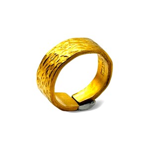 May include: A gold-colored ring with a textured, hammered exterior surface. The band features an open design with a small gap at the bottom, revealing a metallic silver-toned interior component where the two ends meet. The finish is matte and uneven.