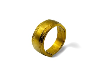Op de afbeelding: Een goudkleurige ring met een brede band met een getextureerde, matte afwerking aan de buitenzijde. De binnenzijde van de band is glad en gepolijst, en de letters "SIS" zijn duidelijk gegraveerd aan de binnenzijde van de metalen ringband.