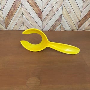 May include: A yellow plastic egg separator with a handle. The separator is designed to separate egg yolks from egg whites.