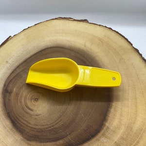 May include: A yellow plastic scoop with a handle. The scoop has a measurement line that says "1/4 cup" on it.