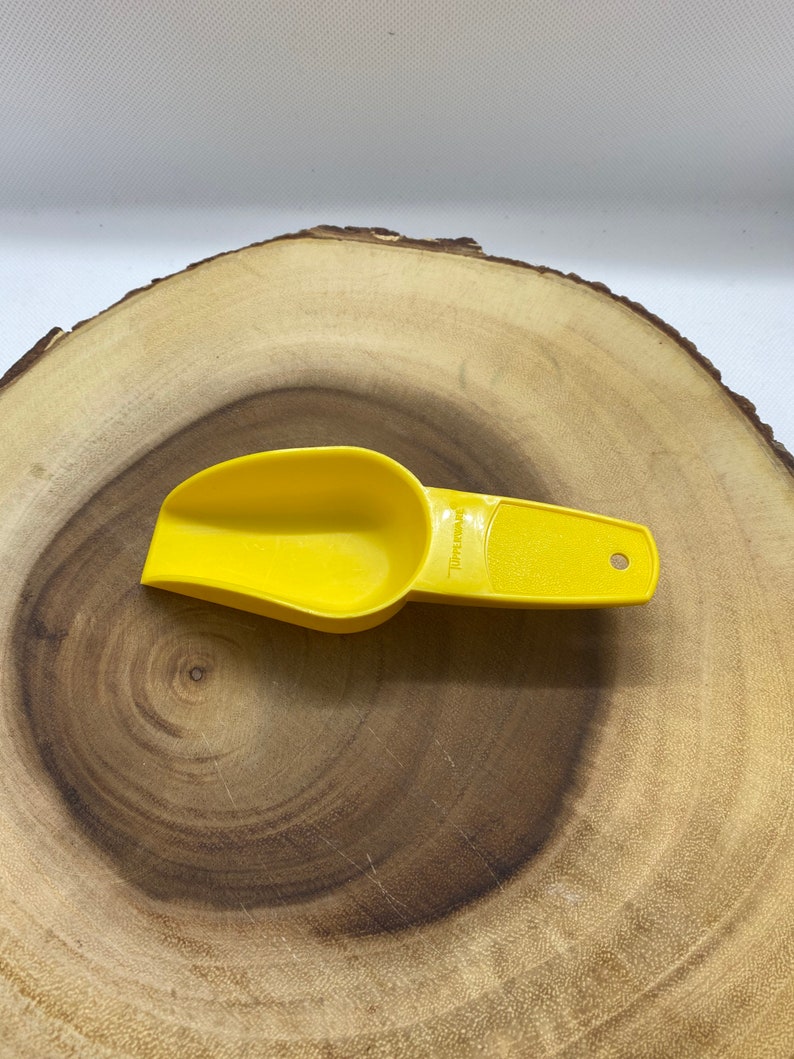 May include: A yellow plastic scoop with a handle. The scoop has a measurement line that says "1/4 cup" on it.