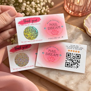 May include: Two rectangular white business cards with pink accents, featuring the text 'thank you!', 'WE HOPE THIS WILL MAKE YOUR DAY!', and 'WE CAN'T WAIT TO SEE YOU AGAIN!'. Each card includes a circular holographic scratch-off sticker, a 'NAIL DREAM' logo with a lotus icon, and a QR code for reviews.