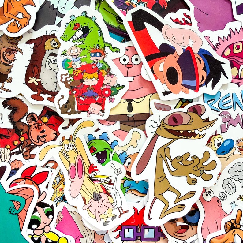 May include: A collection of colorful vinyl stickers featuring various cartoon characters from 1990s television shows, including Ren and Stimpy, the Rugrats, and other animated figures, arranged in a dense, overlapping collage of individual die-cut designs.