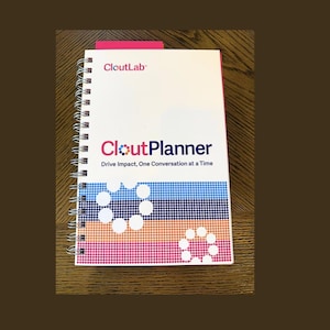 May include: A white spiral-bound planner with the text CloutLab and CloutPlanner Drive Impact, One Conversation at a Time printed on the cover. The design features horizontal bands of blue, purple, orange, and pink dots with two white circular patterns.