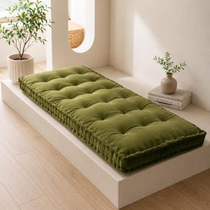 May include: A rectangular olive green tufted floor cushion featuring a soft velvet-like texture and a thick, box-edged construction with multiple button-tufted indentations across the top surface, providing a plush and comfortable seating area.