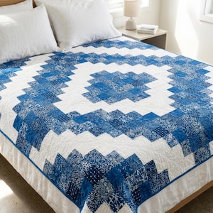May include: A quilt featuring a geometric pattern of blue and white squares arranged in a stepped, concentric design. The blue squares display various intricate patterns, while the white sections are quilted with a subtle, swirling leaf motif.