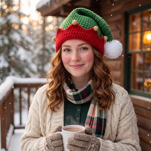 May include: A green and red crocheted elf hat with small tan pom-poms along the brim and a large white pom-pom at the tip. The hat is worn with a beige cable-knit cardigan, a plaid scarf in red, green, and cream, and tan knit gloves.