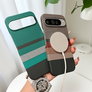 Può includere: Due cover per smartphone con motivo a scacchi. Una cover è verde, nera e bianca con strisce orizzontali. L'altra cover è marrone, beige e nera con un caricabatterie magnetico circolare attaccato sul retro e un ritaglio per l'obiettivo.