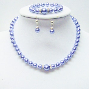 Puede incluir: Un conjunto de joyas de perlas lavanda que incluye un collar, una pulsera y pendientes. Las perlas son de color lavanda claro y tienen un brillo sutil. El conjunto es perfecto para una ocasión especial o para el uso diario.