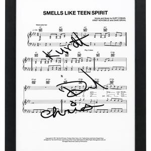 以下が含まれることがあります： カート・コバーン、クリス・ノヴォセリック、デイヴ・グロールによる「Smells Like Teen Spirit」の楽譜の額入りプリント。白い紙には黒い楽譜と歌詞が印刷されており、その上に3つの明確な黒いインクの署名が重ねられています。