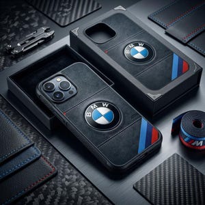 Könnte beinhalten: Eine schwarze Smartphone-Hülle mit einer strukturierten, wildlederartigen Oberfläche, dem BMW-Logo sowie blauen und roten diagonalen Streifen. Die Hülle wird in einer passenden schwarzen Box mit ähnlichem Design präsentiert, neben einem kleinen Marken-Stoffband.