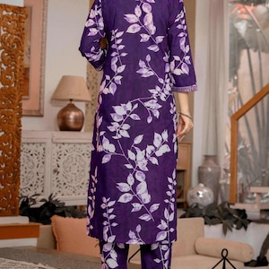 Pu&ograve; includere: Un completo composto da una tunica a maniche lunghe e pantaloni abbinati di colore viola scuro con un motivo a foglie e viticci bianchi. La tunica presenta uno scollo alto con bordo decorativo e maniche a tre quarti con polsini rifiniti.
