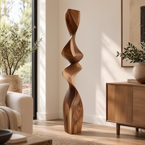 Può includere: Una scultura alta da terra intagliata in legno naturale, caratterizzata da una forma a spirale organica, continua e attorcigliata, con una finitura liscia e lucida che mette in risalto le venature complesse e i caldi toni marroni.
