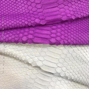 May include: Two layers of textured snakeskin leather, one in a vibrant purple and one in a clean white. The material features a distinct, overlapping scale pattern throughout. The text Zaragoza Tannery is printed vertically along the left side.
