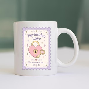 May include: A white ceramic mug featuring a postage stamp-shaped graphic with a light purple border. The design includes a pink heart-shaped padlock, a gold key, and the text "Forbidden Love" above and "Not meant to be... or is it?" below.