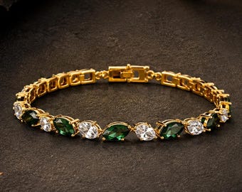 Könnte beinhalten: Ein goldfarbenes Armband mit einem abwechselnden Muster aus smaragdgrünen Steinen im Marquise-Schliff und klaren weißen Steinen im Rundschliff. Das Armband besteht aus einer Reihe verbundener Metallglieder und hat einen sicheren Kastenschloss-Verschluss.
