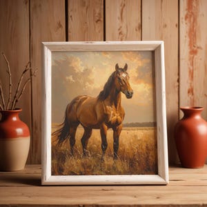Puede incluir: Una lámina de arte enmarcada que muestra un caballo marrón de pie en un campo dorado bajo un cielo nublado. La obra está dentro de un marco de madera blanca desgastada, presentando una representación realista del animal en un paisaje.
