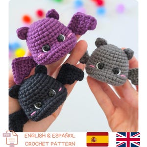 Puede incluir: Tres pequeños murciélagos de peluche tejidos a ganchillo en morado, negro y gris. Cada murciélago tiene ojos de seguridad negros, orejas pequeñas, alas extendidas y mejillas bordadas en rosa. La imagen incluye un icono de PDF y texto que indica un patrón de ganchillo en inglés y español.