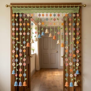 May include: A crochet door curtain featuring a light green lattice header with hanging vertical strands. Each strand consists of small multi-coloured flowers in pink, blue, orange, and white, ending in larger bell-shaped crochet flowers in pastel tones.