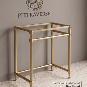 Puede incluir: Un soporte para lavabo de metal chapado en oro con un marco rectangular, cuatro patas verticales y barras de soporte horizontales. El texto PIETRAVERSE y Premium Gold-Plated Sink Stand - Design & Quality son visibles en la imagen.
