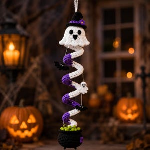 May include: A hanging crochet decoration featuring a white ghost wearing a black witch hat with a purple flower, attached to a white and purple spiral spring. Small black bats and a white ghost are attached to the spring, ending in a black cauldron.