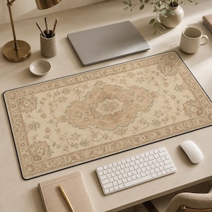 Peut inclure: Un tapis de bureau rectangulaire au fond beige orné d'un motif floral central en médaillon dans des tons sourds de brun clair, vert sauge et rose pâle, fini avec une bordure décorative et un fin liseré noir sur le pourtour.